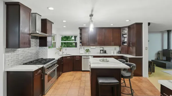 a kitchen with stainless steel appliances a dining table chairs and stove