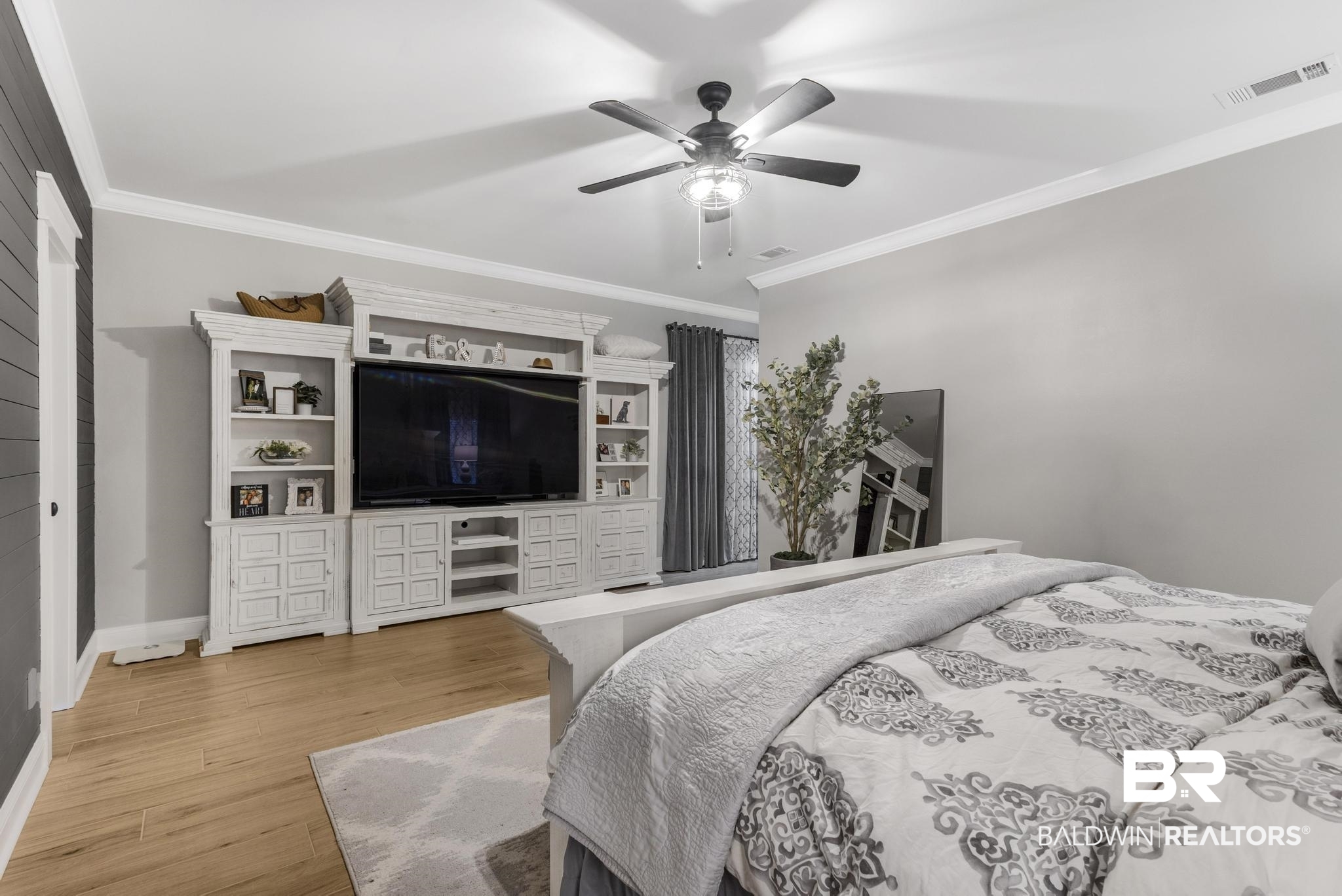 83 Caisson Trace Daphne, AL 36527 - Photo 35 of 63 Built-in media console with storage and shelving, crown molding, a ceiling fan, wood-finish flooring, and shiplap wall accent