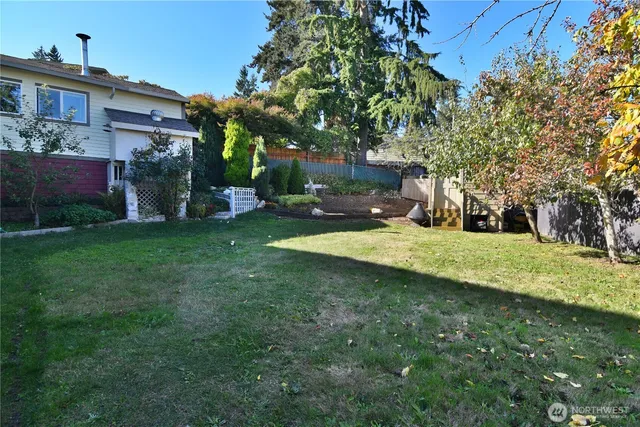 a view of a backyard with wooden fence and flowers