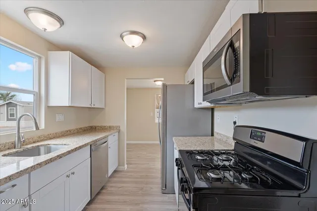 a kitchen with stainless steel appliances granite countertop a stove a sink and a microwave