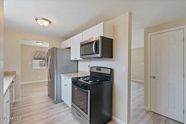 a kitchen with stainless steel appliances a refrigerator a stove top oven and wooden floor