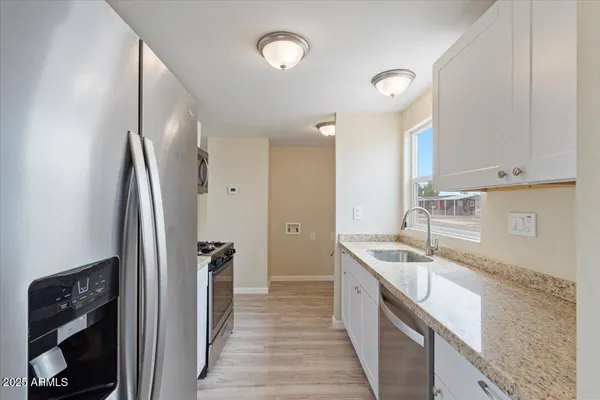 a kitchen with stainless steel appliances granite countertop a sink and a refrigerator