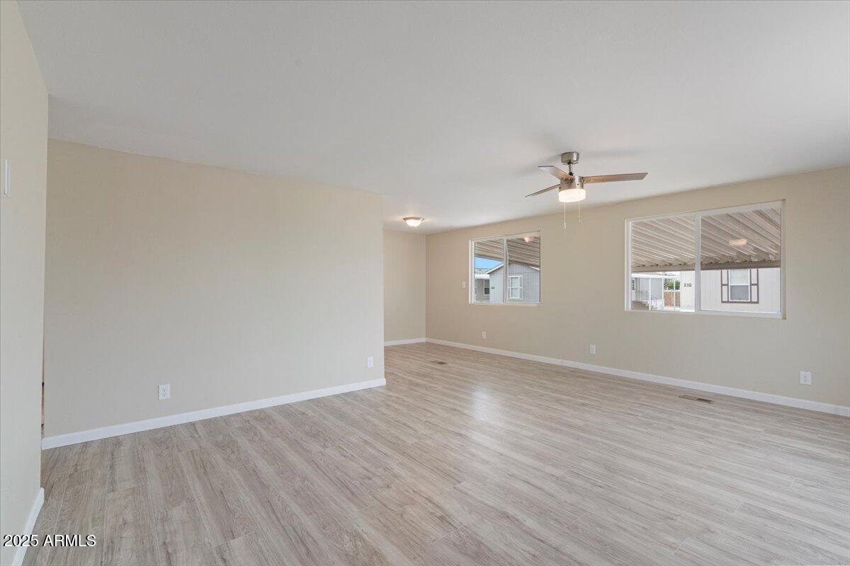 320 East McKellips Road, Unit 209 Mesa, AZ 85201 - Photo 7 of 25 an empty room with wooden floor chandelier fan and windows