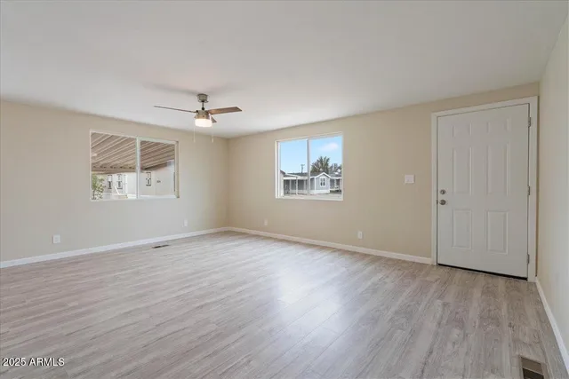 a view of an empty room with a window and wooden floor