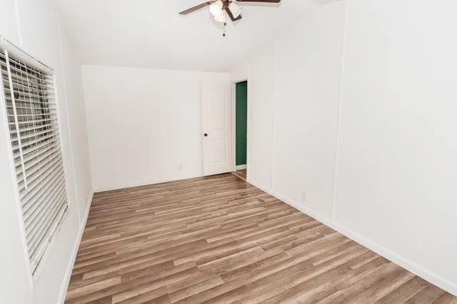 a view of a room with wooden floor and a ceiling fan