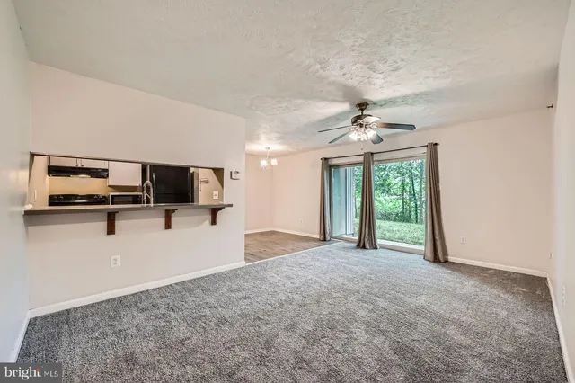 a view of a livingroom with a flat screen tv a ceiling fan and windows