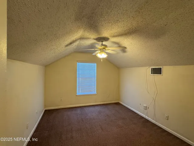 an empty room with a chandelier fan and windows