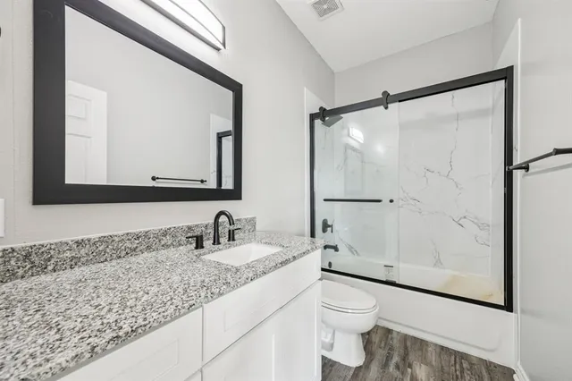 a bathroom with a granite countertop sink toilet and shower