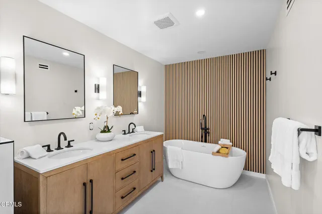 a bathroom with a double vanity sink mirror and bathtub