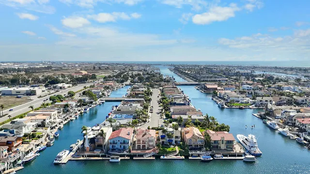 an aerial view of a city with lots of residential buildings ocean and mountain view in back