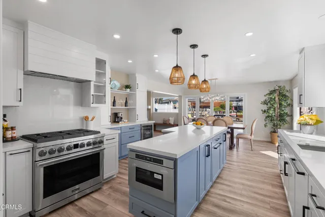 a large kitchen with stainless steel appliances granite countertop a stove and a wooden floors