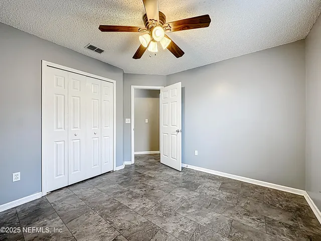 an empty room with closet and a chandelier fan