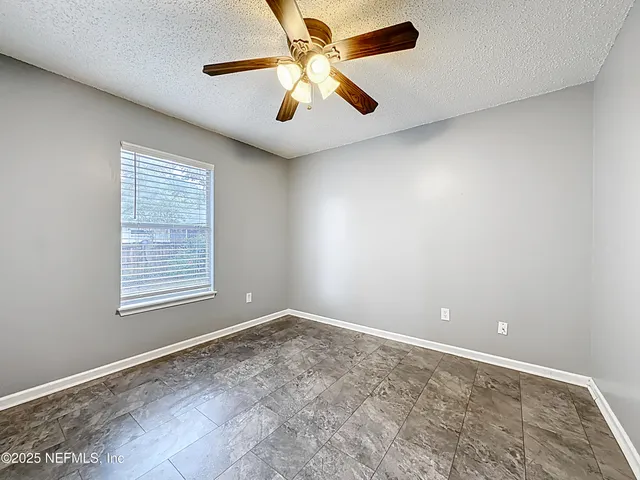 an empty room with a window and a fan