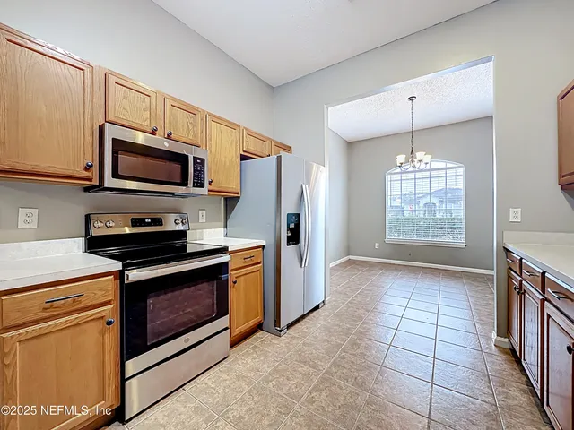 a kitchen with granite countertop a stove a microwave a refrigerator and cabinets