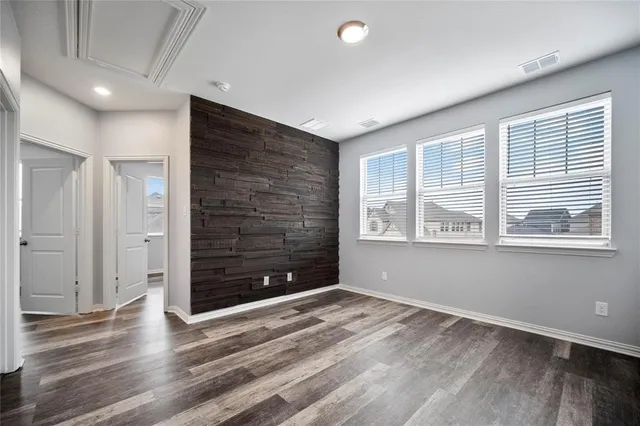 a view of an empty room with wooden floor and window