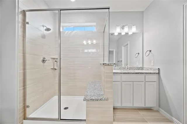 a bathroom with a granite countertop shower sink and mirror