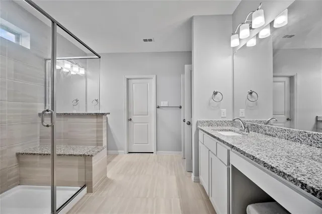 a bathroom with a granite countertop sink a mirror and a shower
