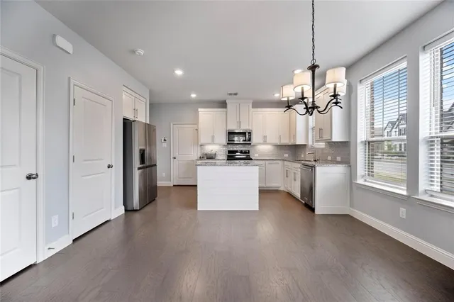 a kitchen with stainless steel appliances granite countertop a refrigerator a oven a stove and a wooden floors