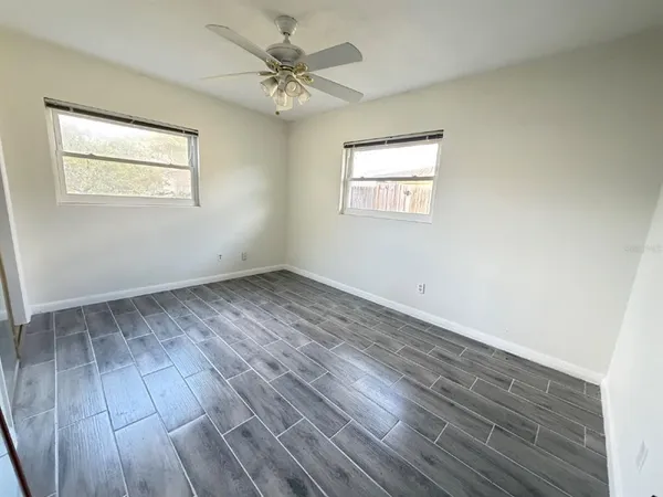 a view of an empty room with wooden floor and a window
