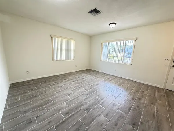 an empty room with wooden floor and windows