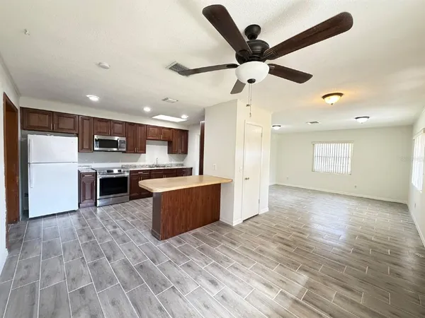 a large kitchen with stainless steel appliances kitchen island granite countertop a stove top oven a sink and a refrigerator