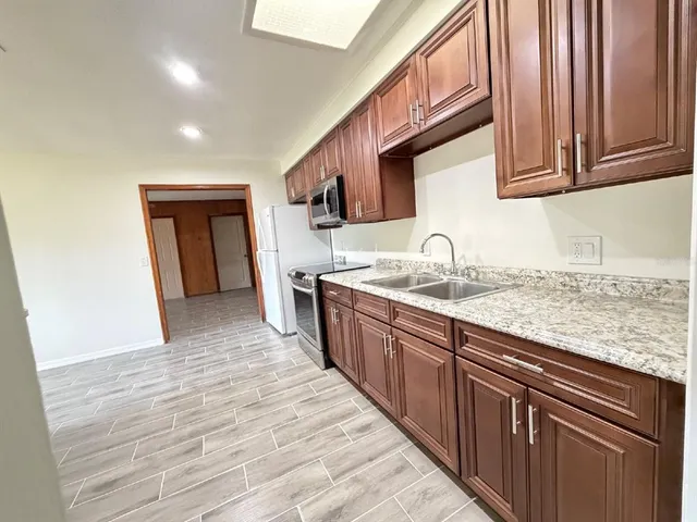 a kitchen with granite countertop wooden cabinets a sink and dishwasher