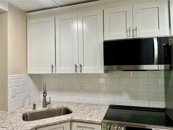 a kitchen with stainless steel appliances granite countertop white cabinets and a sink