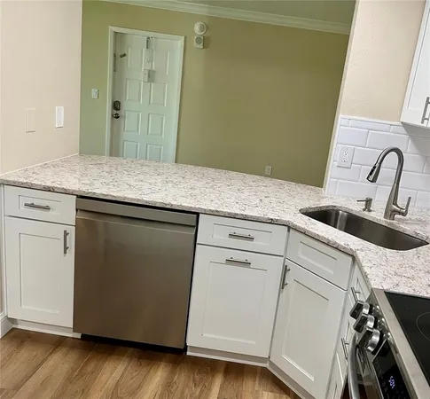 a view with granite countertop a sink and dishwasher a stove with wooden floor