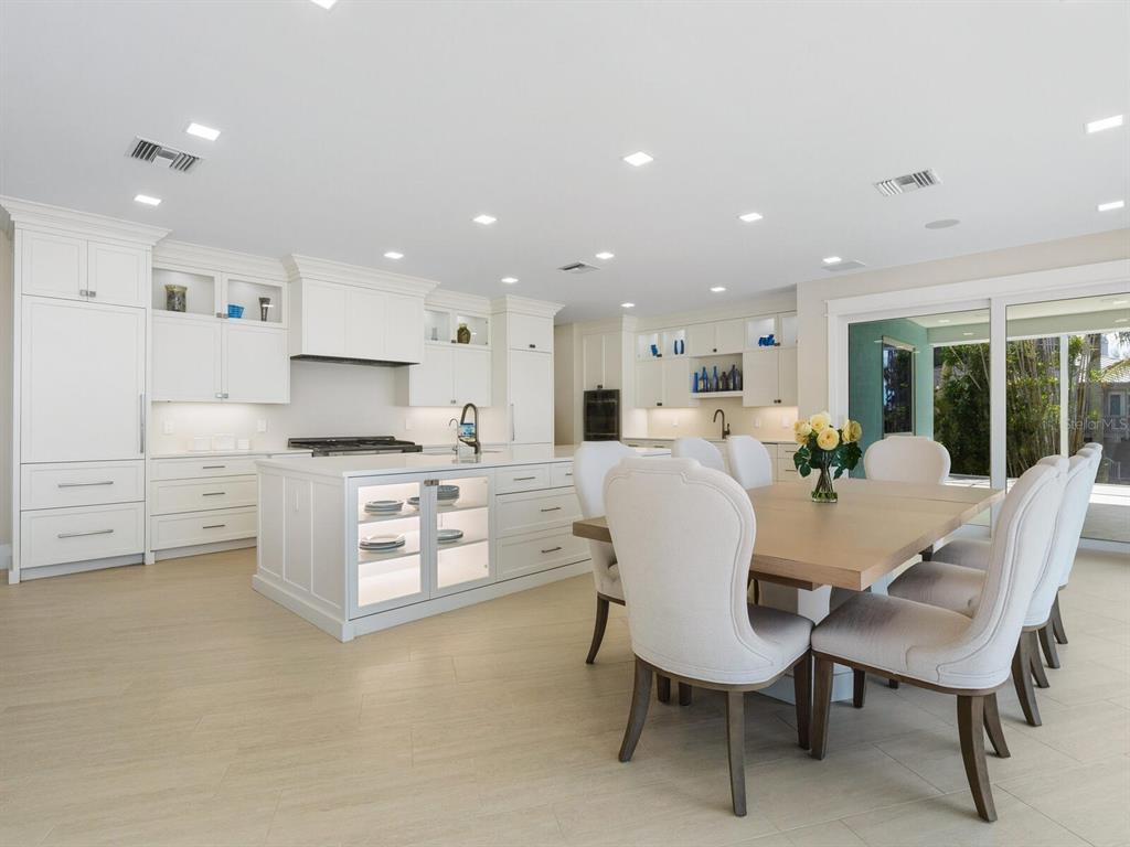 790 North Manasota Key Road Englewood, FL 34223 - Photo 29 of 80 a large kitchen with white cabinets a stove a dining table and chairs