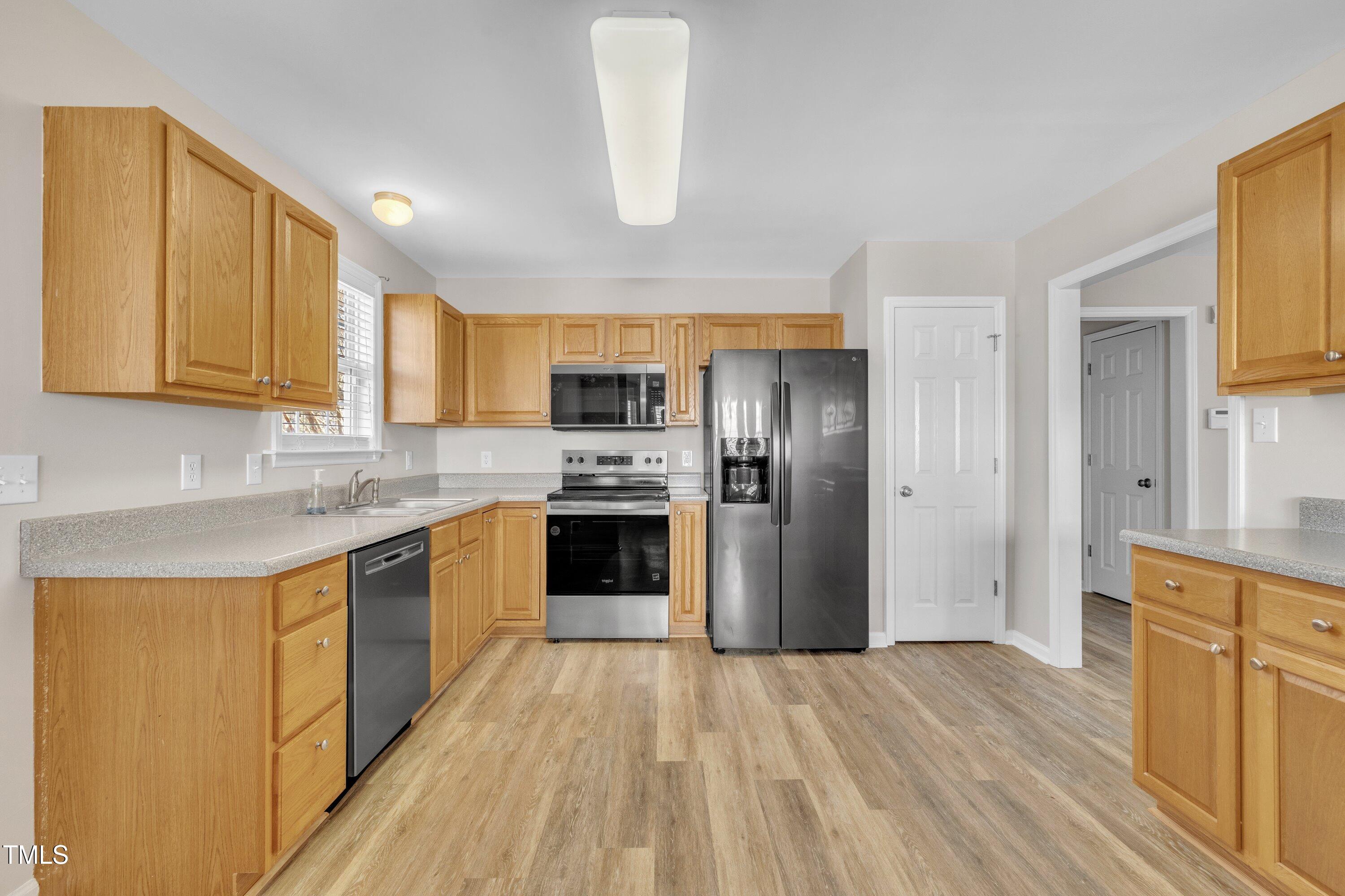 147 Tralee Drive Smithfield, NC 27577 - Photo 27 of 43 a kitchen with stainless steel appliances granite countertop a refrigerator a stove top oven a sink and dishwasher with wooden floor