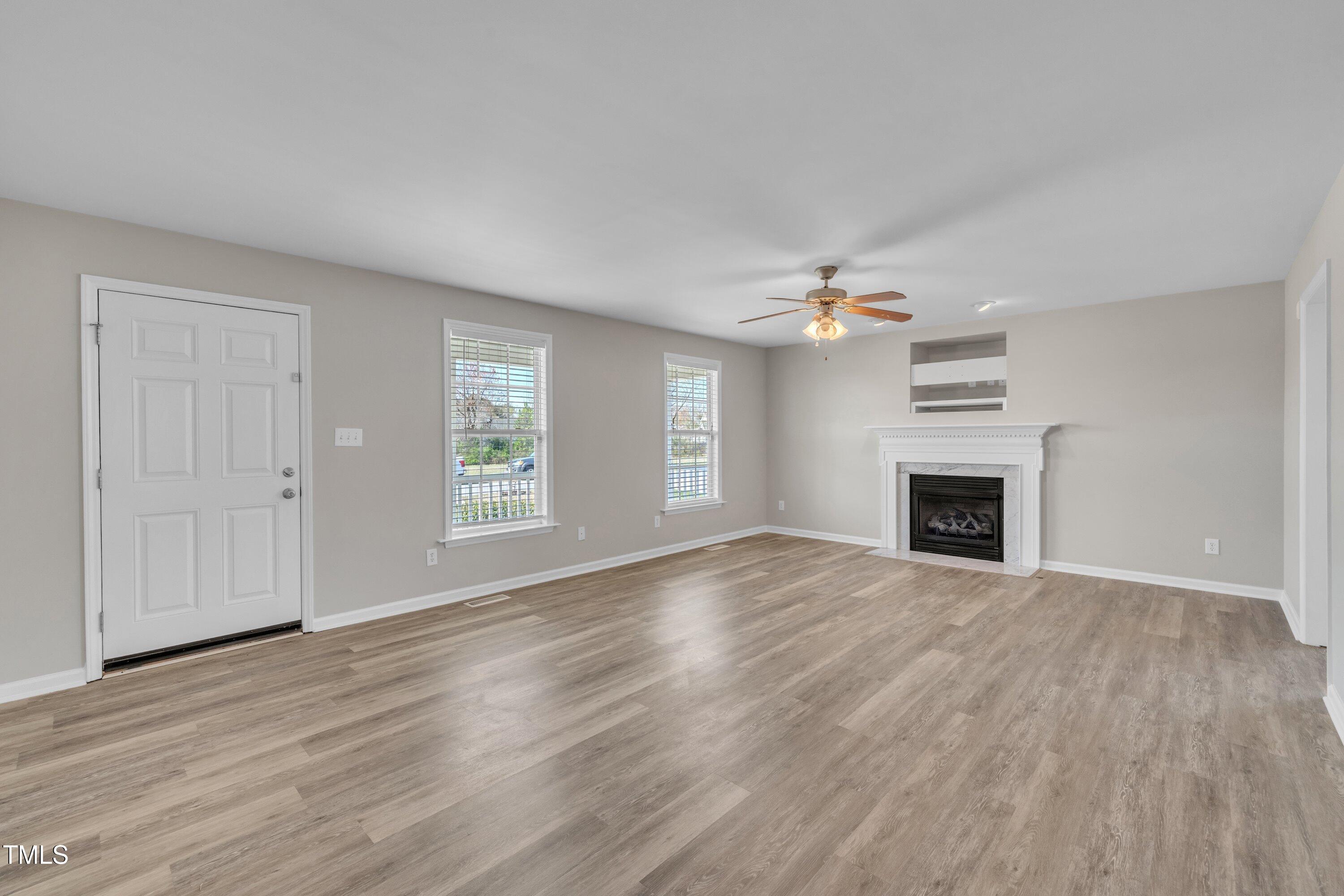 147 Tralee Drive Smithfield, NC 27577 - Photo 9 of 43 an empty room with wooden floor fireplace and windows