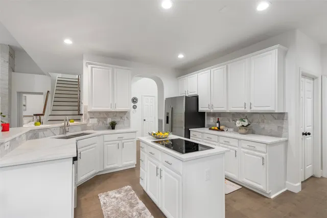 a kitchen with a sink a refrigerator and white cabinets