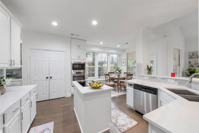 a kitchen that has a lot of white cabinets and stainless steel appliances
