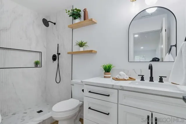 a bathroom with a granite countertop sink a toilet and a shower