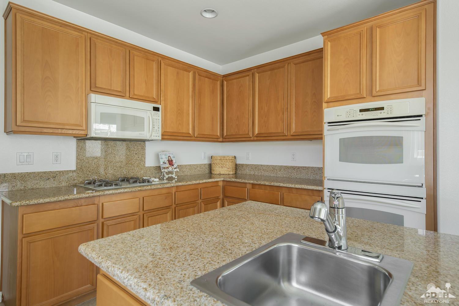 36 Shoreline Drive Rancho Mirage, CA 92270 - Photo 15 of 38 a kitchen with granite countertop a sink stainless steel appliances wooden cabinets and a counter top space