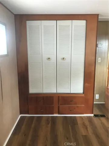 an empty room with wooden floor and cabinet