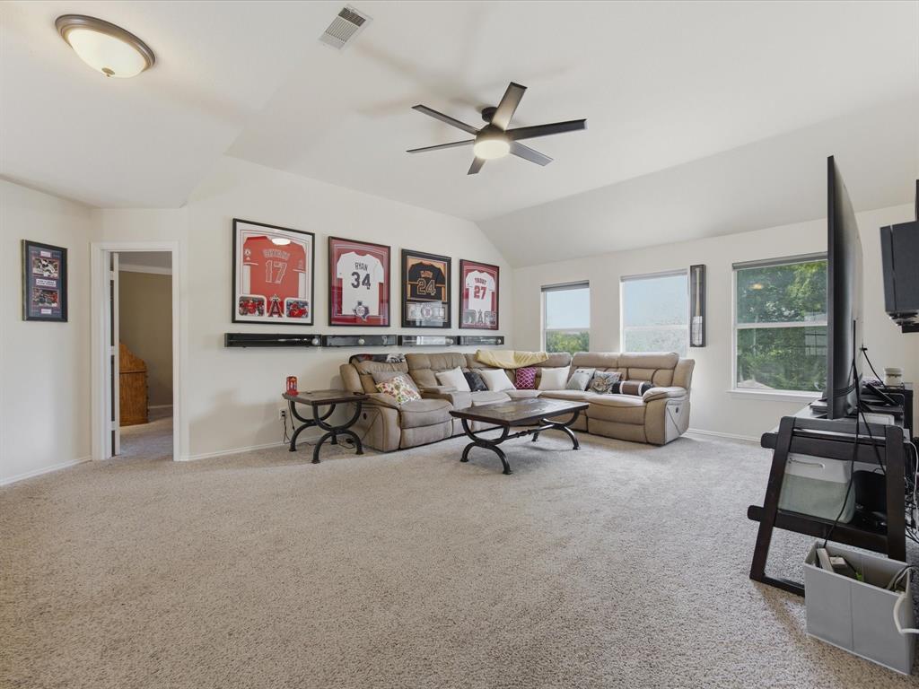 4008 Falcon Ridge Drive Haltom City, TX 76137 - Photo 19 of 40 Spacious bonus room featuring vaulted ceilings, a ceiling fan with integrated lighting, recessed windows with roller shades, and light-toned carpeting