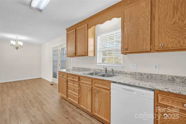 a kitchen with stainless steel appliances granite countertop wooden cabinets a sink and dishwasher with wooden floor