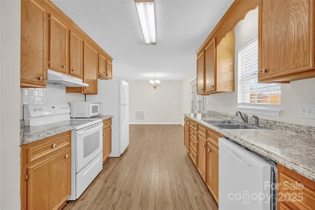 a kitchen with granite countertop a sink a counter space wooden floor and stainless steel appliances