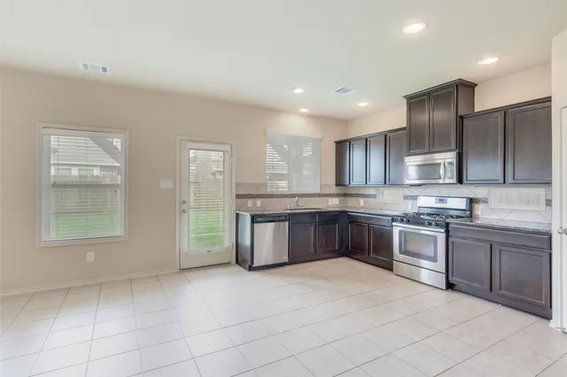 a large kitchen with a large counter top stainless steel appliances and cabinets