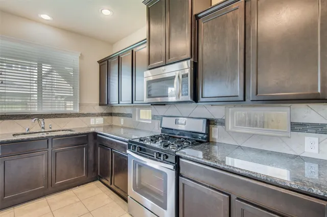 a kitchen with stainless steel appliances granite countertop a sink a stove and microwave