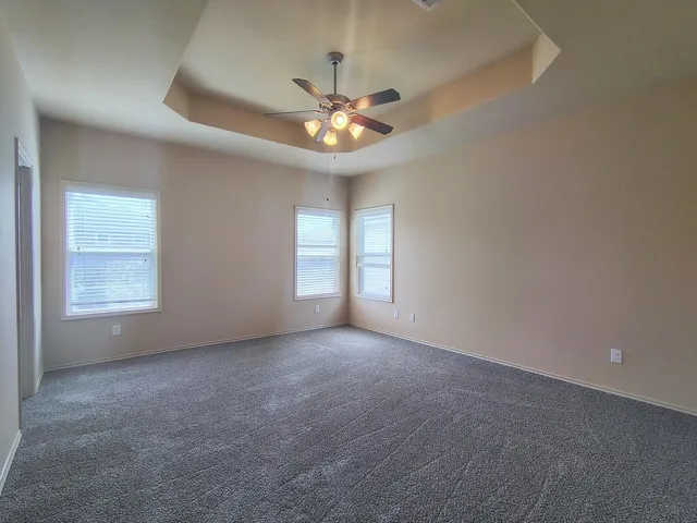 an empty room with windows and fan