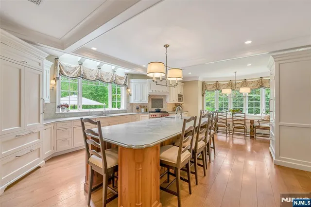 a large kitchen with kitchen island a stove a sink dishwasher and white cabinets with wooden floor