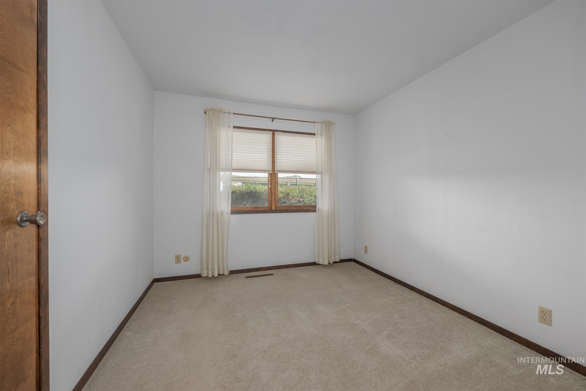 1493 Cove Road Weiser, ID 83672 - Photo 12 of 50 Carpeted room featuring white walls, a wood-framed window with blinds and sheer curtains, and wood trim baseboards