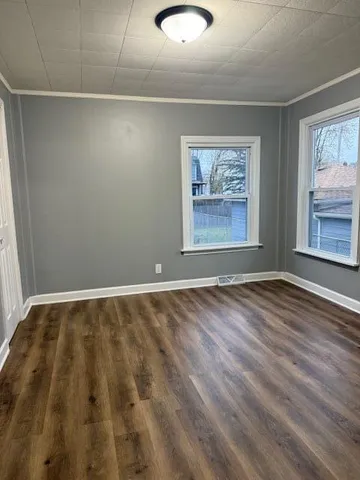 a view of an empty room with window and wooden floor