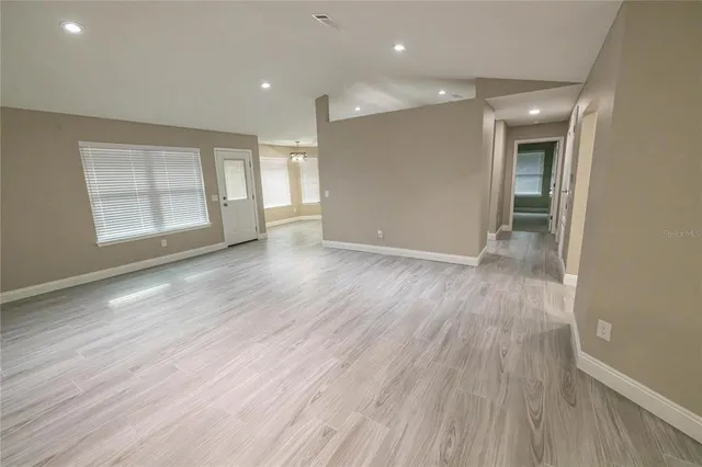 an empty room with wooden floor and windows