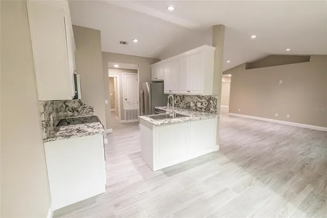 a large kitchen with kitchen island a stove a sink dishwasher and a refrigerator with wooden floor