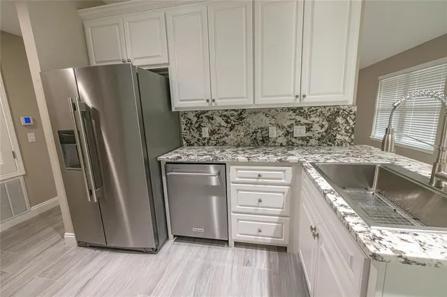 a kitchen with granite countertop a refrigerator and a sink