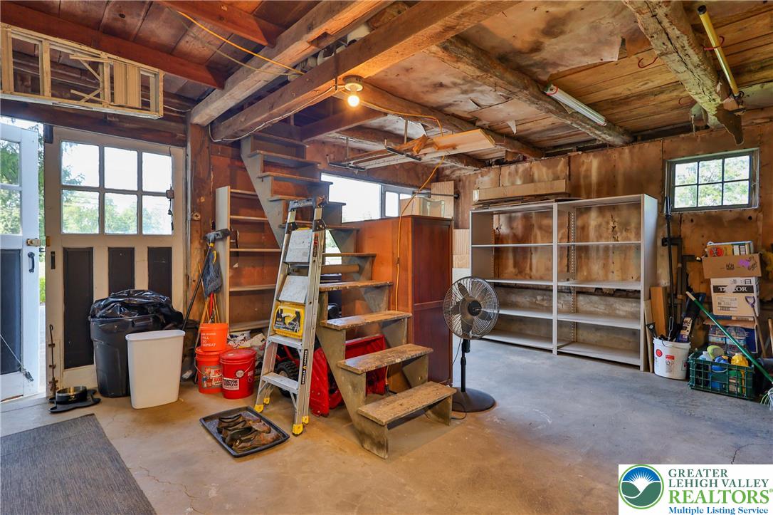 666 Point Phillips Road Bath, PA 18014 - Photo 47 of 68 A utilitarian garage space offers abundant storage, exposed wooden beams, and an accessible staircase.