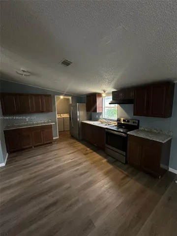 a kitchen with stainless steel appliances kitchen island granite countertop a refrigerator and a stove top oven